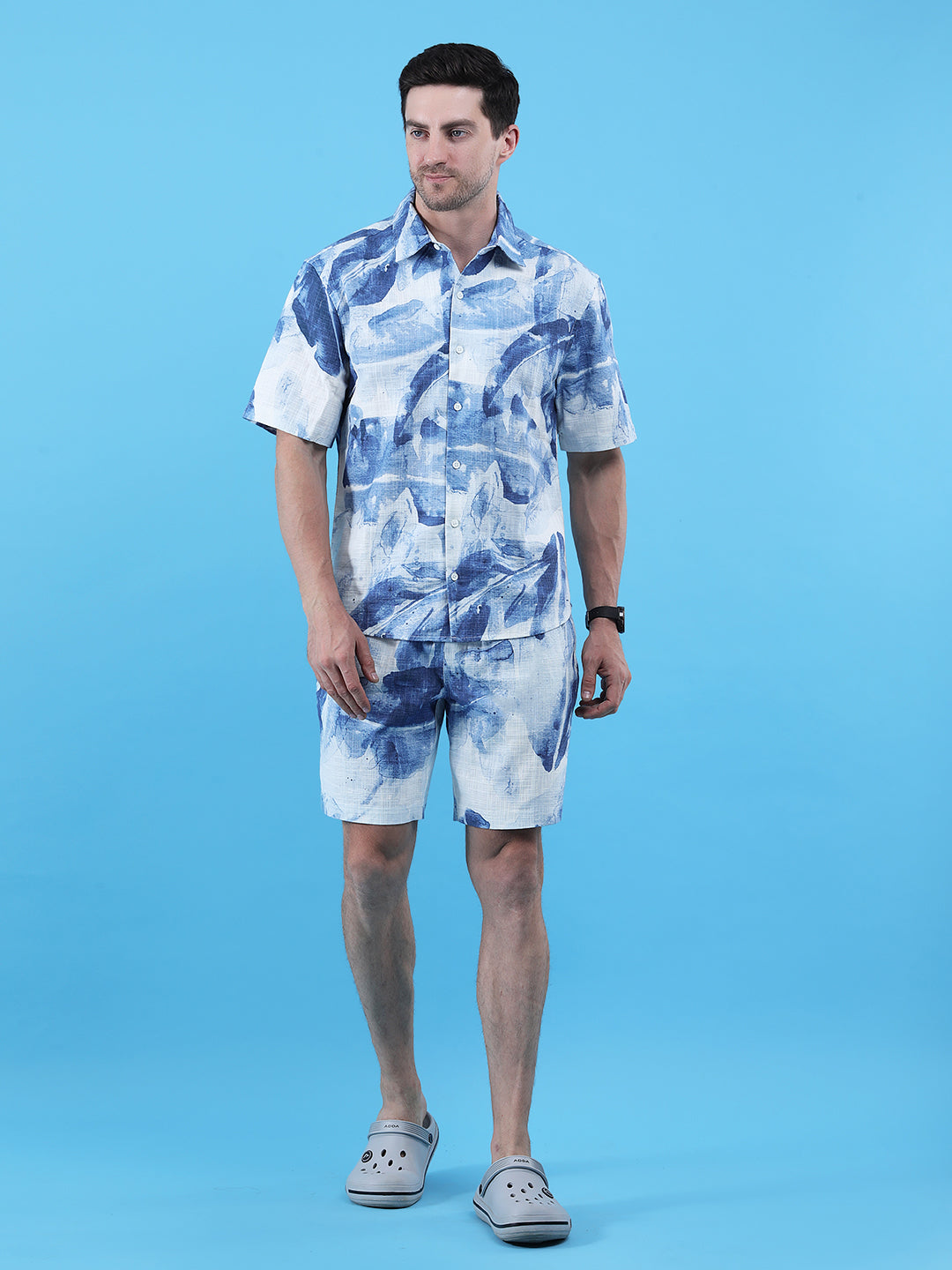 Man wearing a blue and white patterned shirt and shorts on a blue background